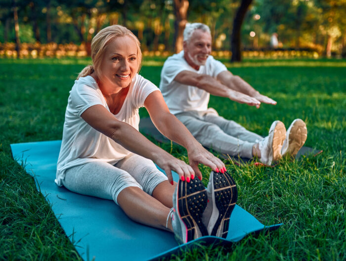woman and man stretching on mats in park